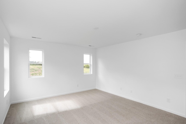 unfurnished room with carpet floors, visible vents, and baseboards