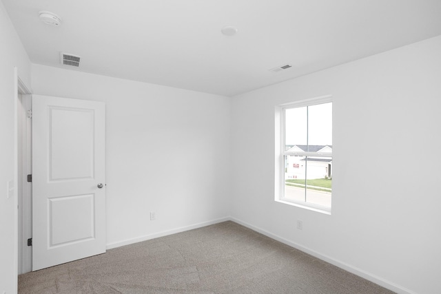 empty room with carpet, visible vents, and baseboards