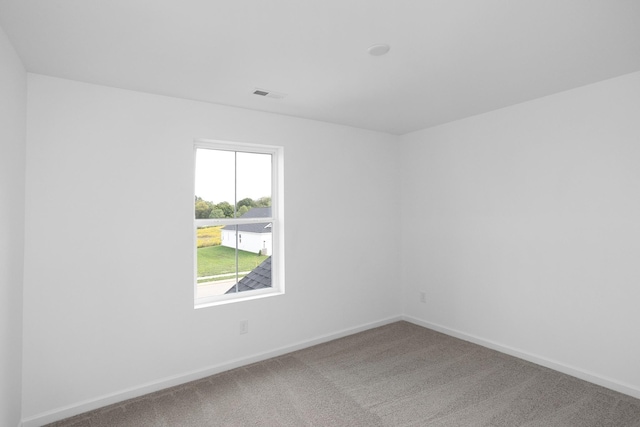 carpeted spare room with visible vents and baseboards