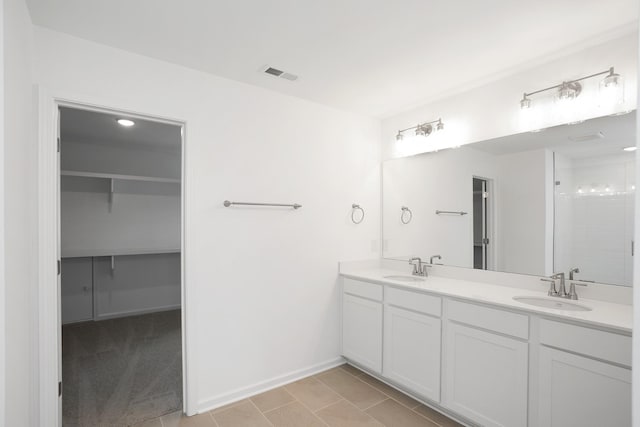 full bathroom with double vanity, a sink, visible vents, and baseboards