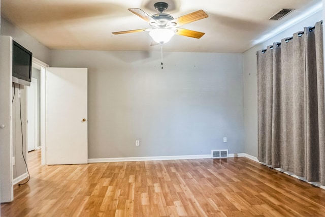 empty room with baseboards, light wood finished floors, visible vents, and a ceiling fan