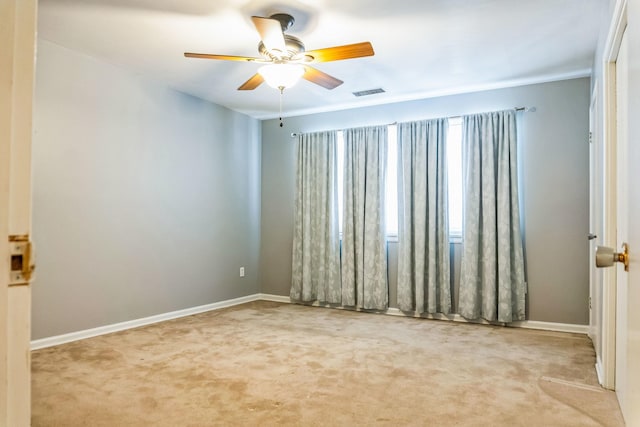 carpeted empty room featuring baseboards, visible vents, and a ceiling fan