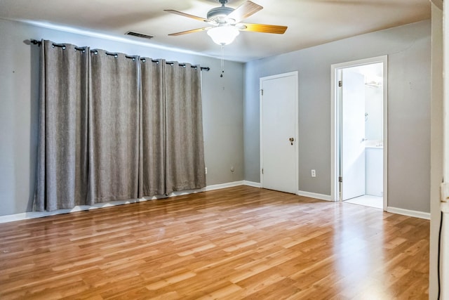 spare room with baseboards, ceiling fan, visible vents, and wood finished floors