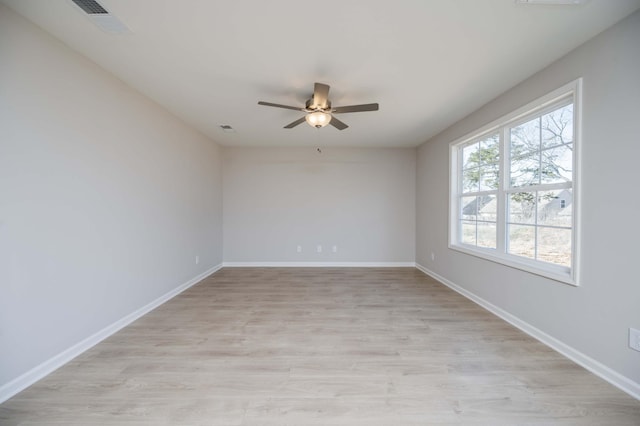 spare room featuring light wood-style flooring, visible vents, baseboards, and ceiling fan