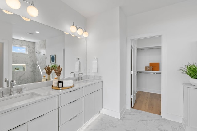 bathroom with marble finish floor, a marble finish shower, baseboards, and a sink