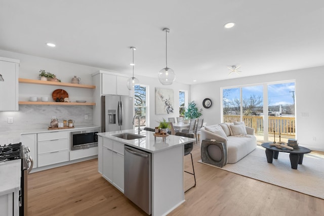 kitchen featuring light wood finished floors, white cabinetry, appliances with stainless steel finishes, and a sink