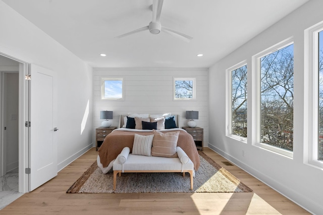 bedroom featuring light wood-style floors, ceiling fan, visible vents, and baseboards