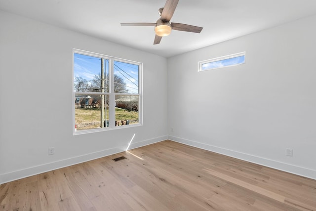 empty room featuring a ceiling fan, light wood-type flooring, visible vents, and baseboards