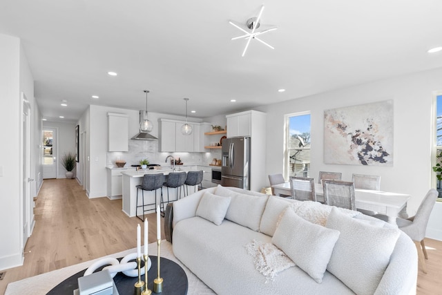 living area featuring baseboards, light wood-type flooring, and recessed lighting