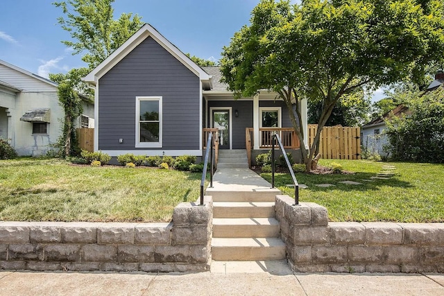 view of front of home featuring a porch, a front yard, fence, and a shingled roof