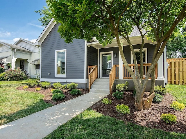 view of front of house with a porch, a front yard, and fence