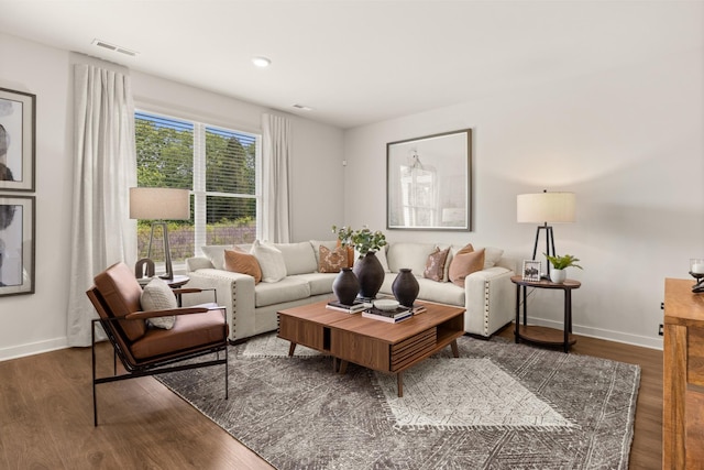 living room with wood finished floors, visible vents, and baseboards