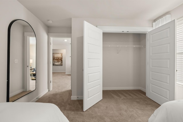 carpeted bedroom featuring baseboards and a closet