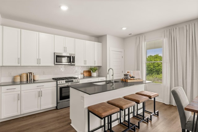 kitchen with appliances with stainless steel finishes, dark wood-style flooring, a sink, and decorative backsplash