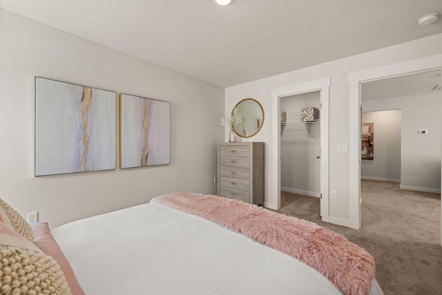 bedroom featuring a closet, carpet, a walk in closet, and baseboards