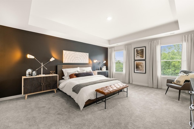 bedroom featuring a raised ceiling, carpet flooring, baseboards, and multiple windows