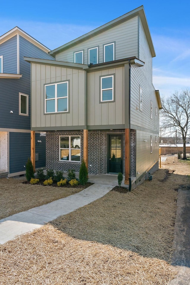 view of front of home featuring board and batten siding and brick siding