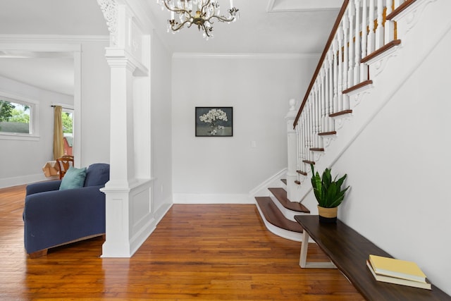 foyer featuring baseboards, crown molding, ornate columns, and wood finished floors