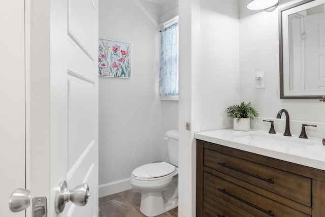 bathroom with baseboards, vanity, and toilet