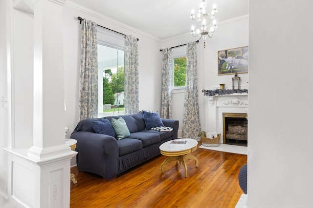 living area with a fireplace with flush hearth, a chandelier, ornamental molding, and wood finished floors