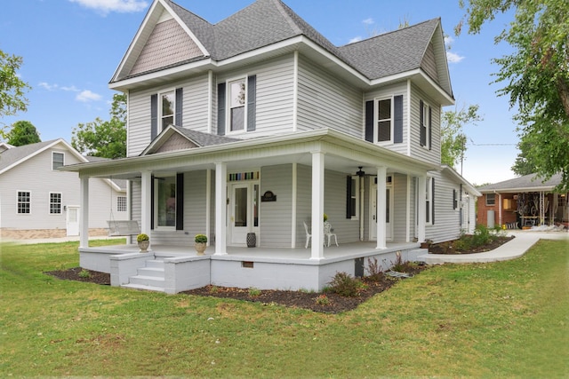 view of front of house featuring covered porch, a shingled roof, and a front yard