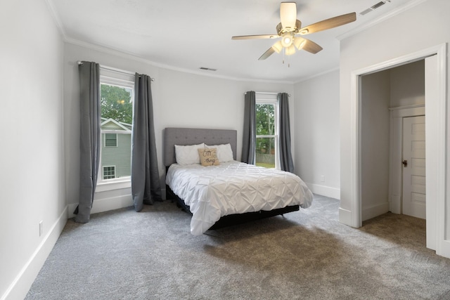 carpeted bedroom featuring ornamental molding, multiple windows, and visible vents