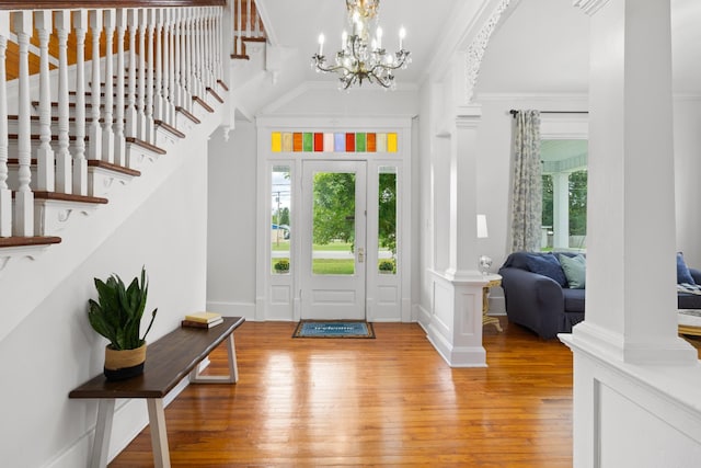 entrance foyer with a notable chandelier, light wood-type flooring, plenty of natural light, and crown molding