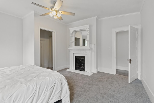 carpeted bedroom featuring baseboards, a fireplace with flush hearth, a ceiling fan, and crown molding