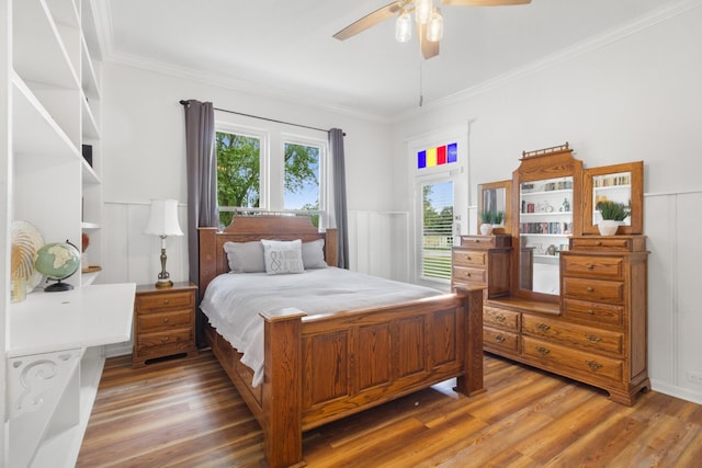 bedroom with a wainscoted wall, crown molding, ceiling fan, and wood finished floors