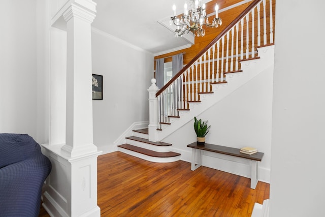 stairway with ornamental molding, baseboards, ornate columns, and wood finished floors