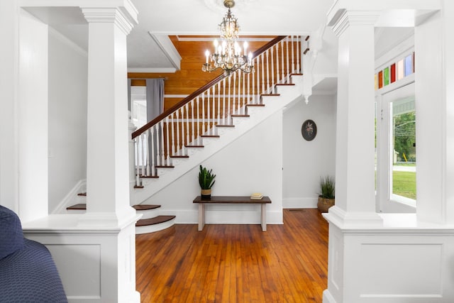 stairway featuring baseboards, ornamental molding, wood-type flooring, and ornate columns