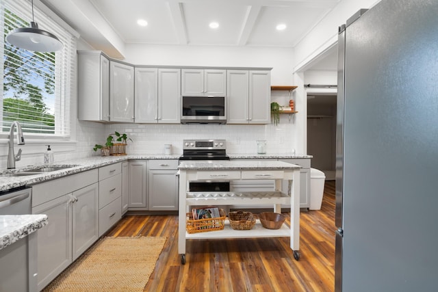 kitchen featuring backsplash, gray cabinetry, appliances with stainless steel finishes, a sink, and wood finished floors