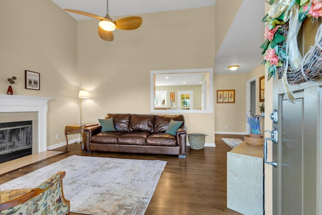 living area with a ceiling fan, dark wood-style flooring, a high end fireplace, and baseboards