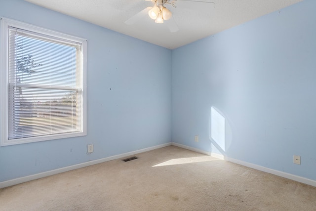 carpeted empty room with visible vents, ceiling fan, and baseboards