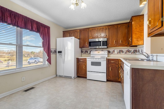 kitchen with light countertops, white appliances, a sink, and brown cabinets