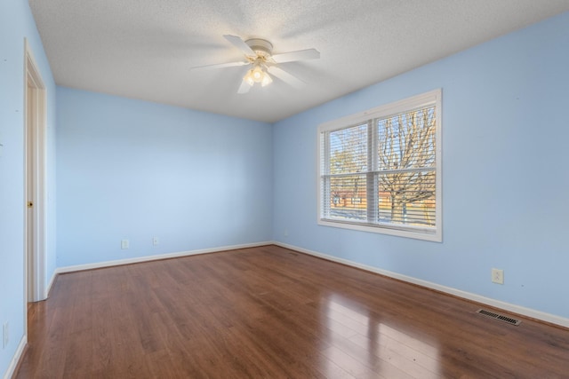 unfurnished room featuring visible vents, a ceiling fan, a textured ceiling, wood finished floors, and baseboards