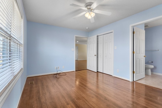 unfurnished bedroom with a closet, ceiling fan, baseboards, and wood finished floors