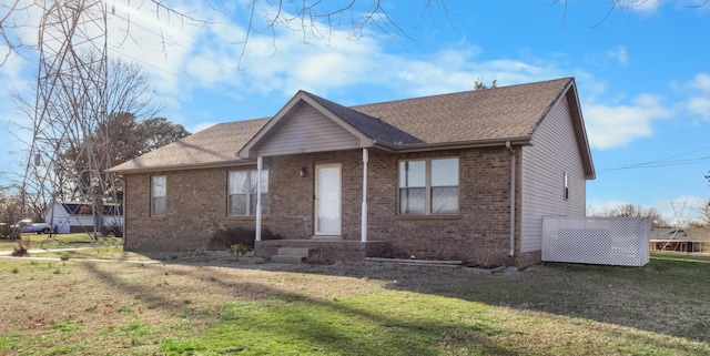 ranch-style home featuring brick siding, a front yard, and a shingled roof