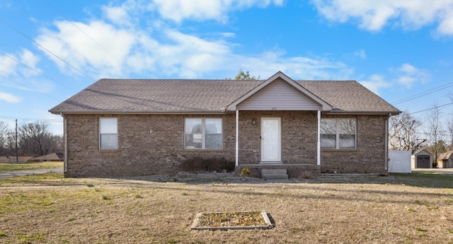 single story home featuring a front yard, brick siding, and roof with shingles