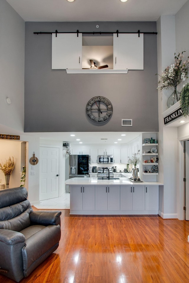 bar featuring stainless steel appliances, a barn door, a high ceiling, and visible vents