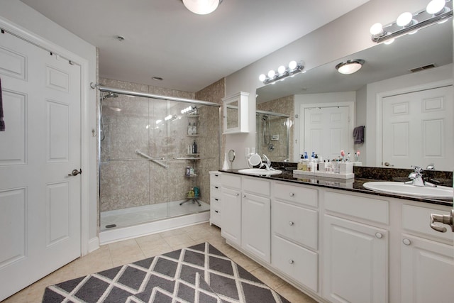 bathroom featuring visible vents, a sink, a shower stall, and double vanity