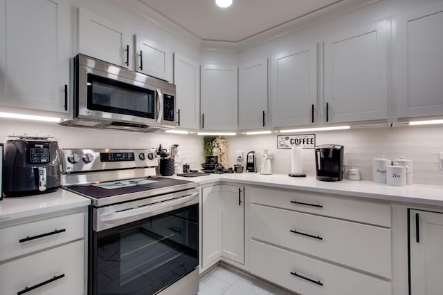 kitchen featuring white cabinets, marble finish floor, light countertops, appliances with stainless steel finishes, and backsplash