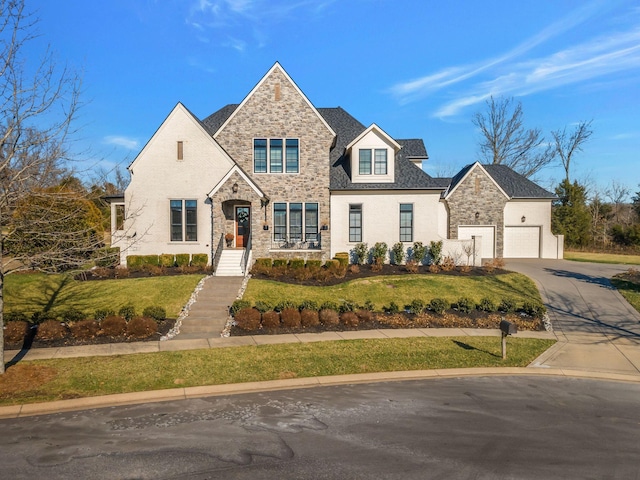 view of front of property featuring a garage, stone siding, driveway, and a front yard