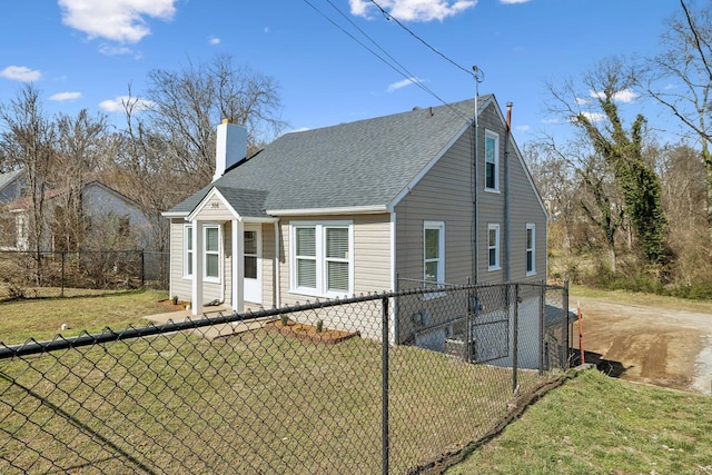 view of front of house featuring roof with shingles, a chimney, a front yard, and fence