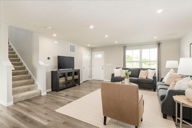 living area with recessed lighting, wood finished floors, visible vents, baseboards, and stairway