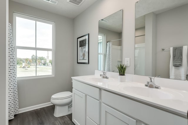 full bathroom featuring visible vents, a sink, toilet, and wood finished floors