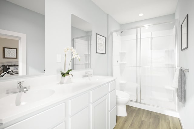 bathroom featuring wood finished floors, a stall shower, a sink, and toilet