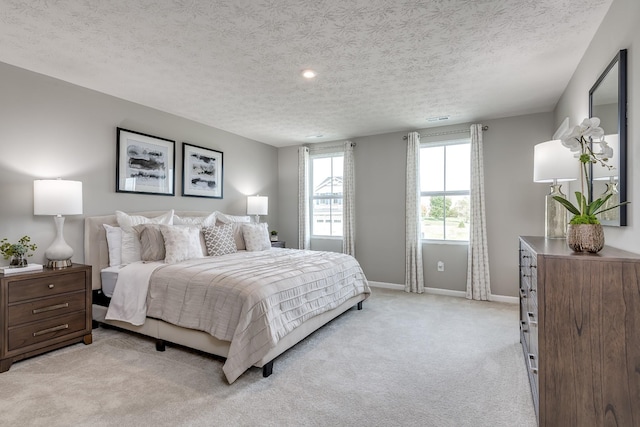 bedroom with baseboards, a textured ceiling, and light colored carpet