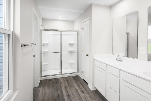 full bathroom with double vanity, a sink, a shower stall, and wood finished floors