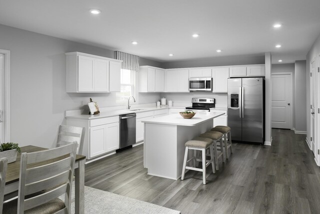 kitchen featuring recessed lighting, stainless steel appliances, dark wood-style flooring, a kitchen island, and a sink